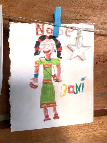 A child’s drawing depicting Bonnie Raechal as Ngäbe hangs on the Volunteer's house.