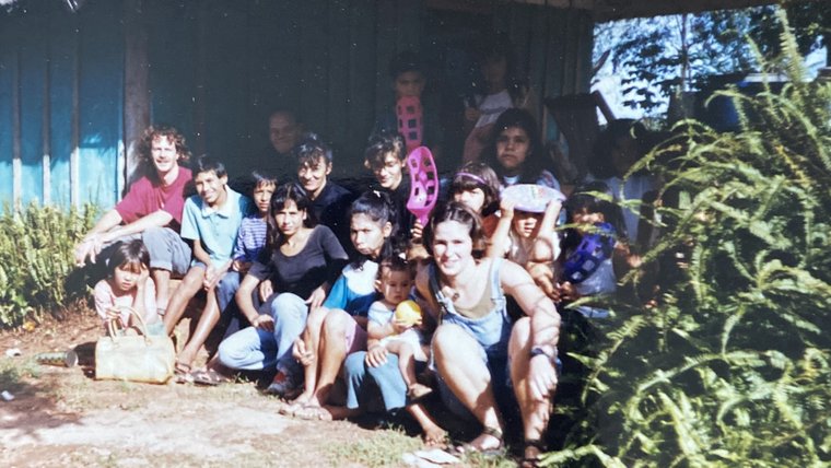 Chris Lins sits with community members on the steps of a home in Paraguay.