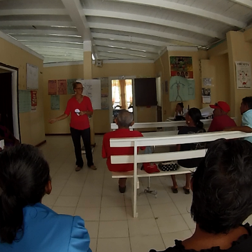 People stand and sit in a room listening to health care workers give lessons.