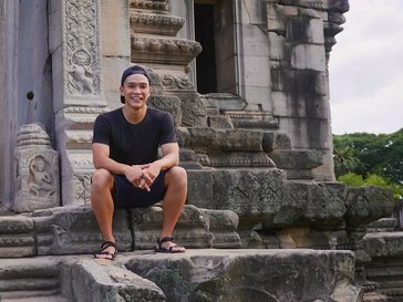 A man sits on the steps of an ancient building