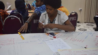 Woman sitting at a table working on posters