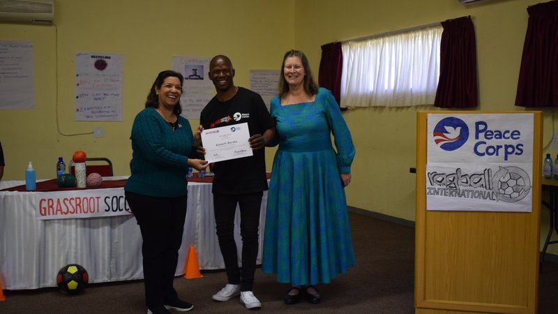 A picture of Coach Kenny getting a certificate from CD and Madam Ambassador