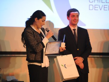 On left individual has a mic and certificate and one individual on right