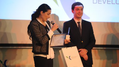On left individual has a mic and certificate and one individual on right