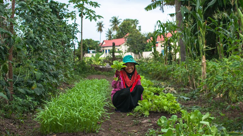 A woman with her newly-grown produce in her garden.
