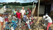 Dave Gorman and Tumi Taabe pose with kids on bikes