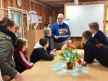 Older American man teaches Moldovan students in a library.