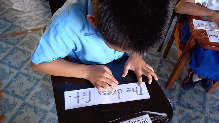 A young child reads 'the dress fit' on a strip of paper.