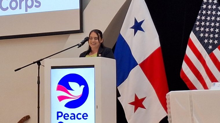 Dena, a female Peace Corps Volunteer in Panama, stands behind a Peace Corps podium