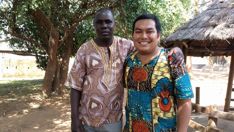 A young man of Native American heritage stands outside next to an older man of Zambian heritage.