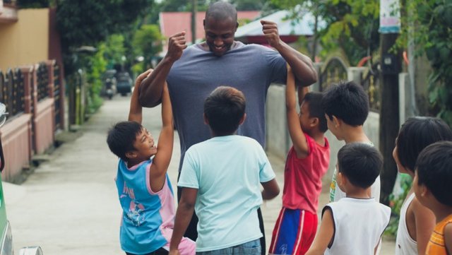A Children, Youth, and Family Volunteer playing with children in his host community.