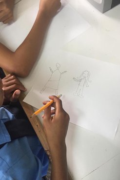 Up close shot of Jamaican student drawing with yellow pencil in a white classroom