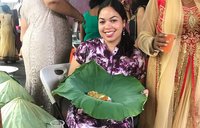 Volunteer sitting displaying seven curry in lily leaf at local wedding