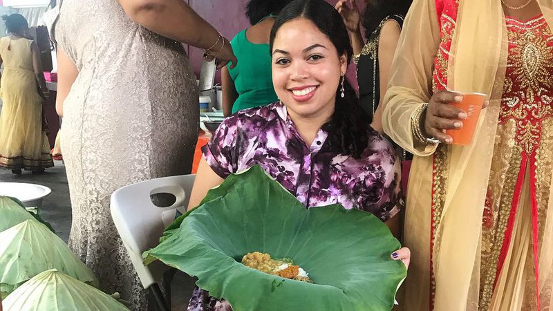 Volunteer sitting displaying seven curry in lily leaf at local wedding