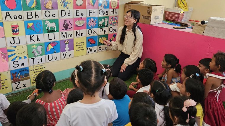 Education Volunteer teaching the English alphabet to elementary level students