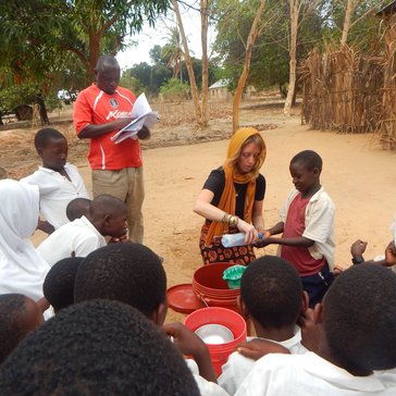 Emily's 6-year-old neighbor helping her demonstrate handwashing for the Mazingira Mazuri crowd after making a handwashing sta