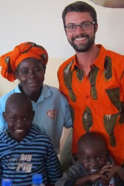 Peace Corps Volunteer Andrew Farr stands with a mother and her children.