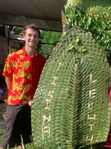Christian next to a fan woven by Fijian women for a regional celebration.