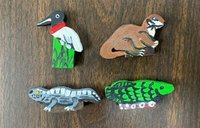 Four wooden, hand-painted, flat animals who serve as game pieces