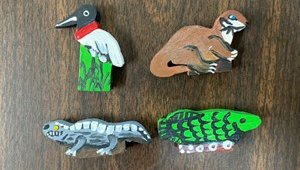 Four wooden, hand-painted, flat animals who serve as game pieces