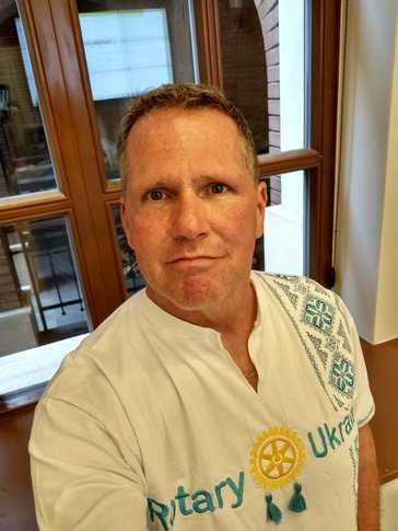 A middle-aged man wears a white shirt with Rotary Ukraine embroidered