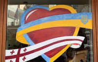 A storefront window features art depicting a heart with Ukraine and Georgia's flags.