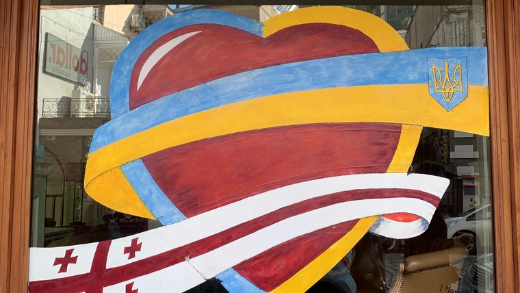 A storefront window features art depicting a heart with Ukraine and Georgia's flags.