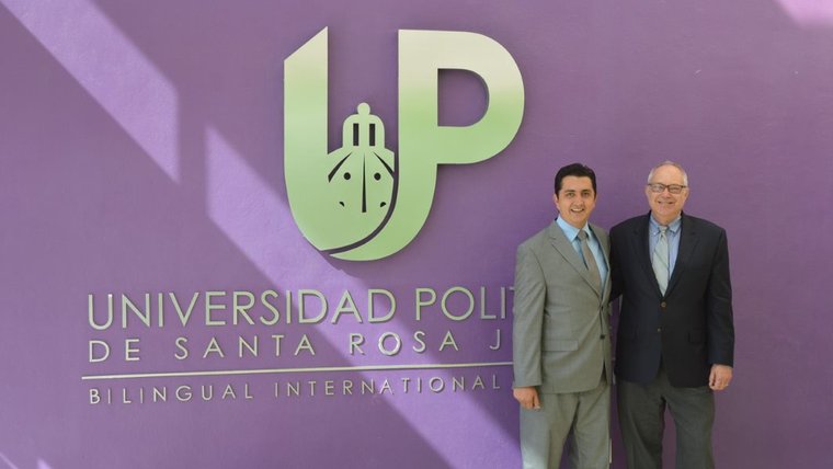 Two people standing in front of university sign.