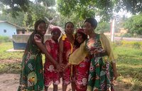 A group of five black female smiling persons join hands
