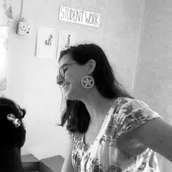 A white teacher smiles while she work with two Jamaican primary students