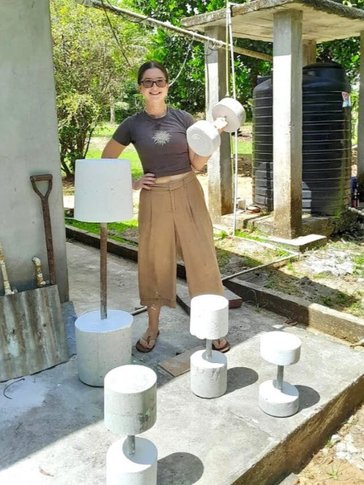 A young woman lifts a cement gym weight