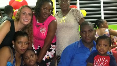A Peace Corps Volunteer stands with her host family in Dominica.