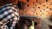 Justin and a community member construct a fuel-efficient cookstove