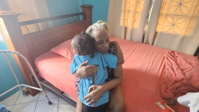 A child hugs an elderly participant in the reading program in Saint Lucia.