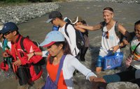 A Volunteer walks arm in arm with a group of Filipinos along the coast.