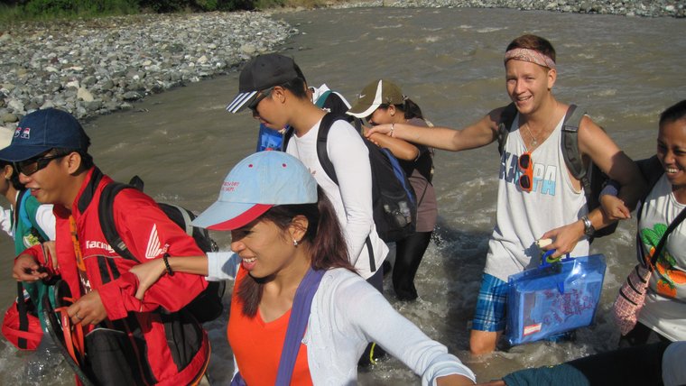 A Volunteer walks arm in arm with a group of Filipinos along the coast.