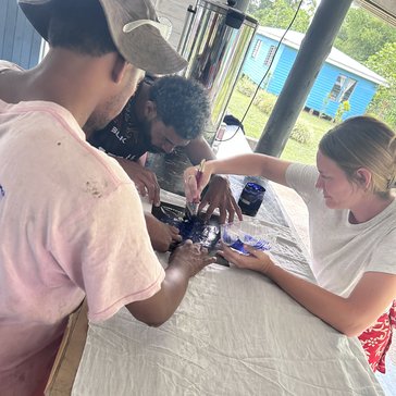 Emily hand paints sulus with a couple of village youth.