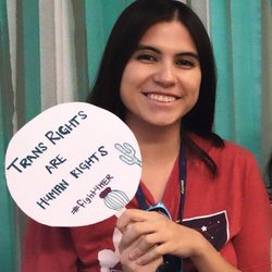 A young woman holds a "Trans rights are human rights" sign.