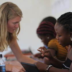 Volunteer Katlyn bends over to help a Malawian female fill out some doucments.