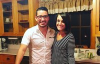 A Peruvian man and a white woman stand together by a table and smile