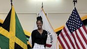 PCV Mya Lowe in front of two flags