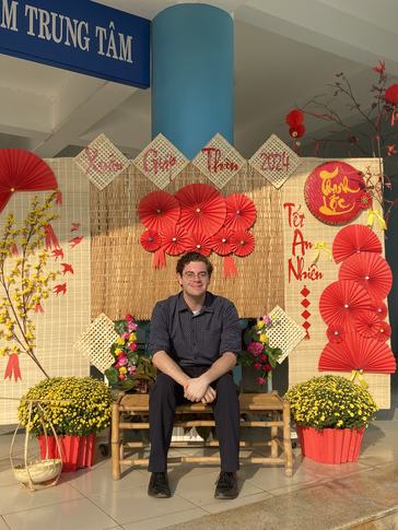 Matthew poses with Tết decorations arranged by students in his community.