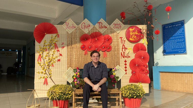 Matthew poses with Tết decorations arranged by students in his community.