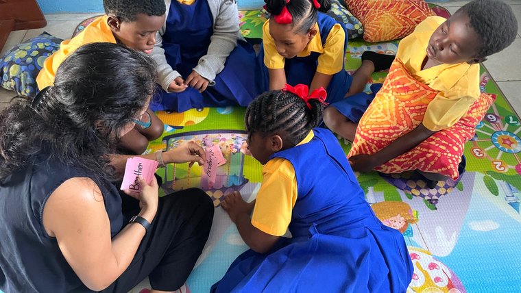 Ileana seated on mat with pillows and 5 students and word cards