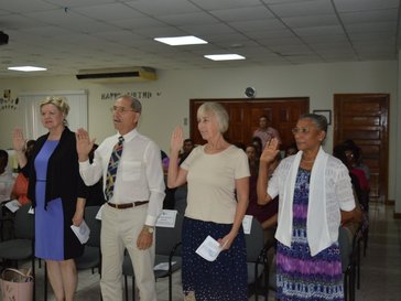 Four people standing up with right hand up