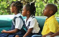 Three young students dressed in uniforms look into the distance.