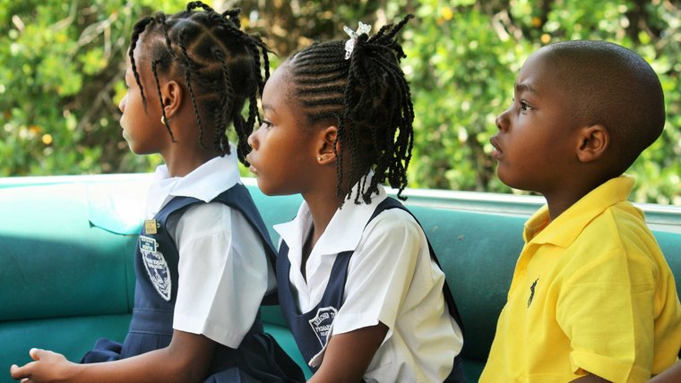 Three young students dressed in uniforms look into the distance.