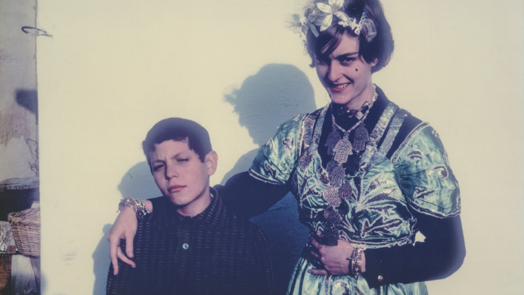 A young woman stands with her arm around a young boy.
