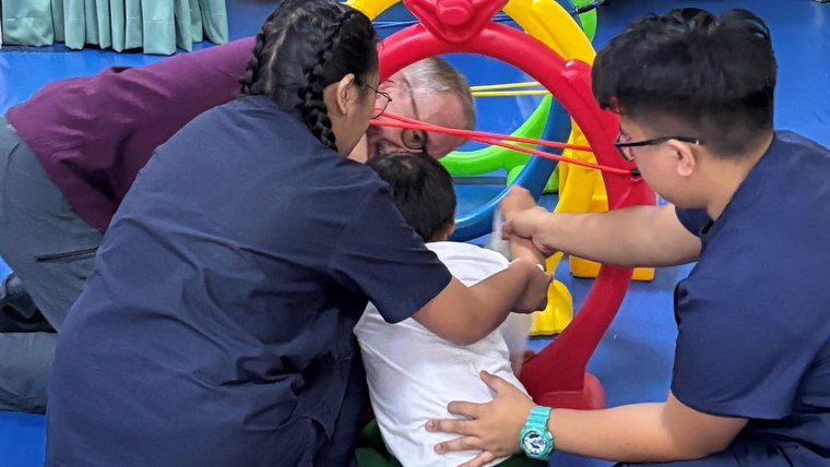 Johan and his counterparts interact with a physical therapy patient in the Philippines.