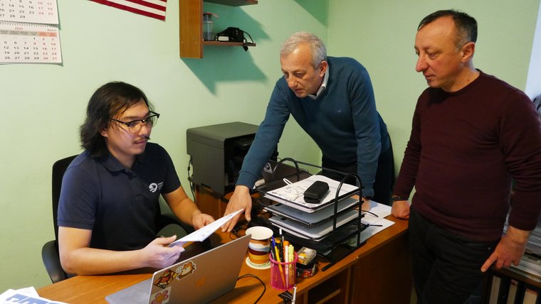 Volunteer sitting at a desk with papers and a laptop working with his counterparts.